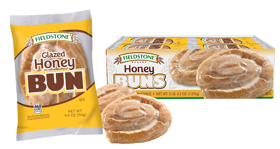 A yellow and white package with a glazed honey bun pastry showing through the clear cellophane in the middle of the packaging. Two unwrapped honey buns are pictured behind the package. A carton of honey buns is in the background.