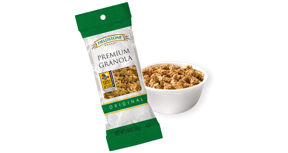 A green and white package of premium 1 grain granola. A white bowl of granola sits to the right of the package of granola.