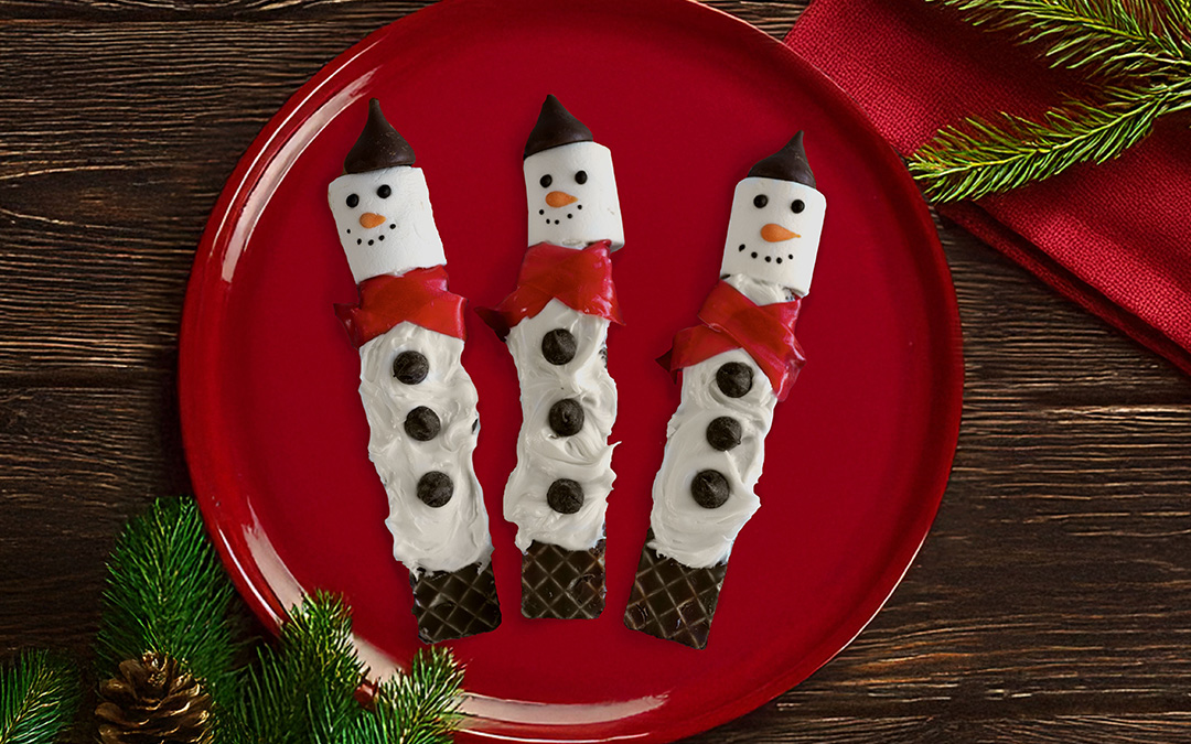 Three nutty buddy bars decorated to look like snowmen sit on a red plate